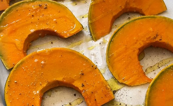 Adding roasting ingredients to pumpkin on a roasting tray