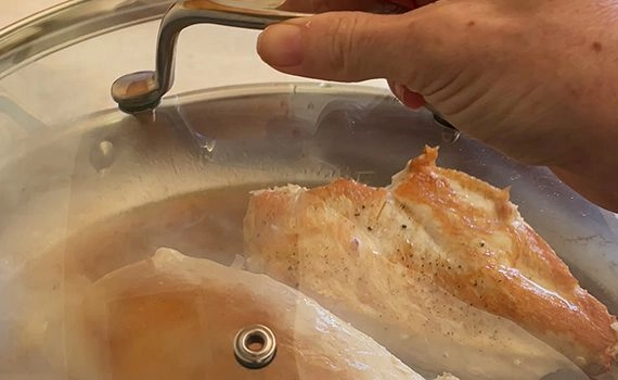 Adding lid to a pan to steam the chicken