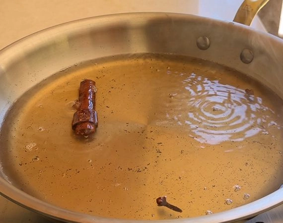 A pan filled with poaching liquid spices and vanilla.