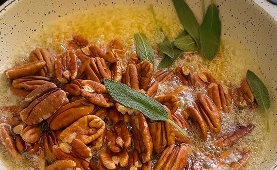 Bubbling melted butter with pecans and sage in a saucepan