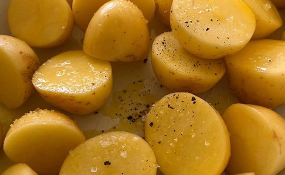 Salt, pepper and olive oil added to cut potatoes
