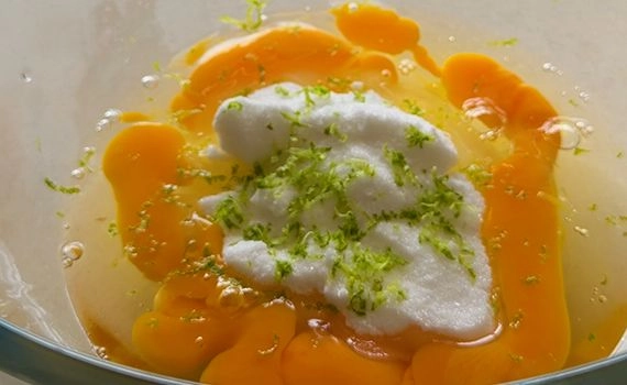 Eggs, sugar and lime zest on a bowl.