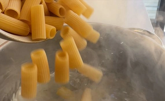 Adding rigatoni to a pot of boiling water