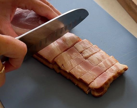 Slicing bacon on a chopping board.