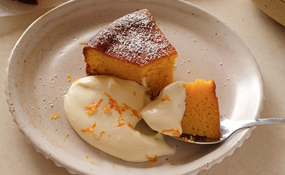 A slice of clementine cake served with cheesecake citrus cream.