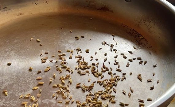 Fennel seeds toasting in a fry pan.
