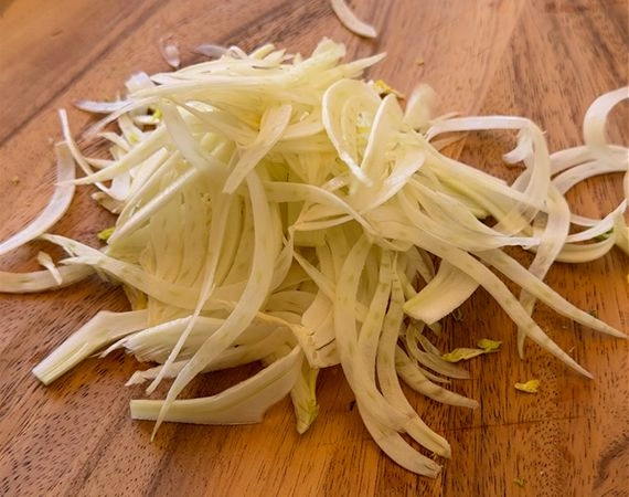 Shaved fennel on a chopping board.