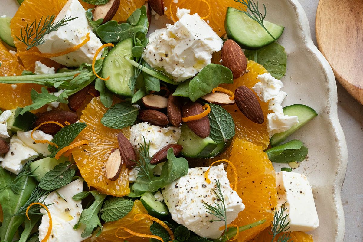 A plate of orange salad with feta, cucumber and herbs