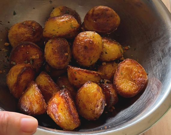 Roasted potatoes in a bowl with rosemary chopped tossed through