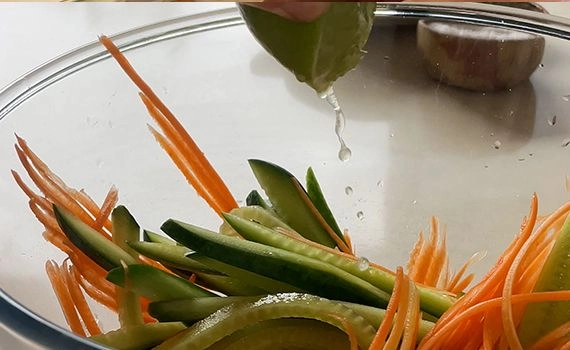 Adding lime juice to carrot and cucumber to make a pickle