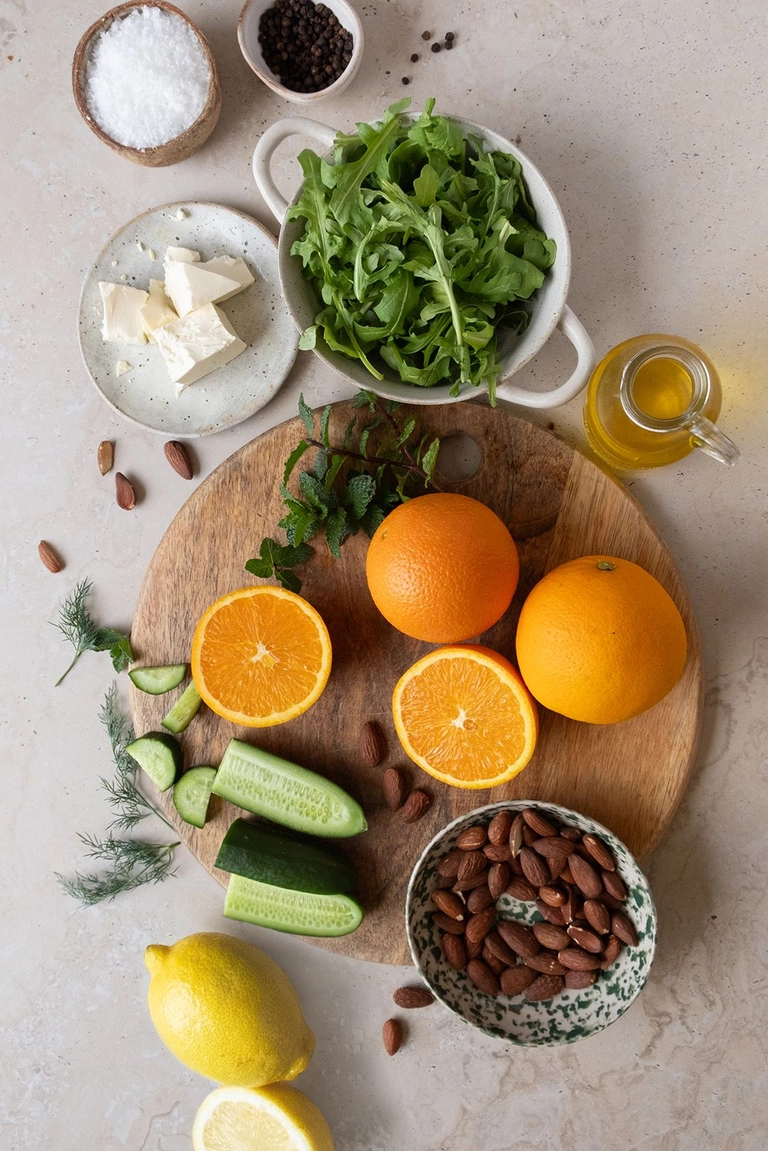 Ingredients to make orange salad with feta, cucumber and herbs