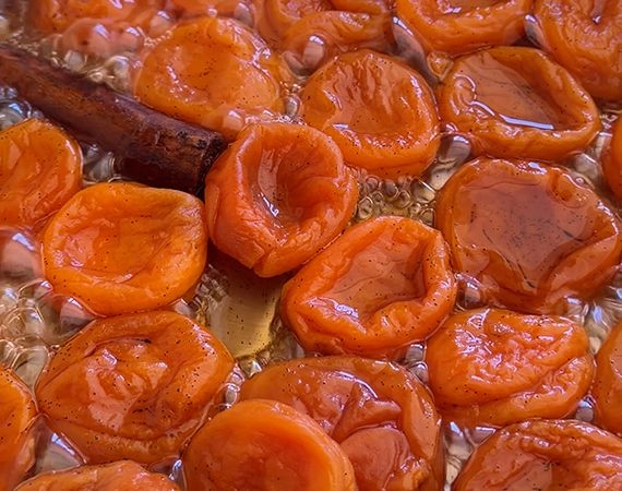 Apricots simmering in poaching liquid.