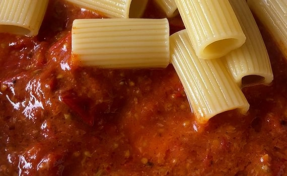 Adding cooked rigatoni to the roasted tomato sauce