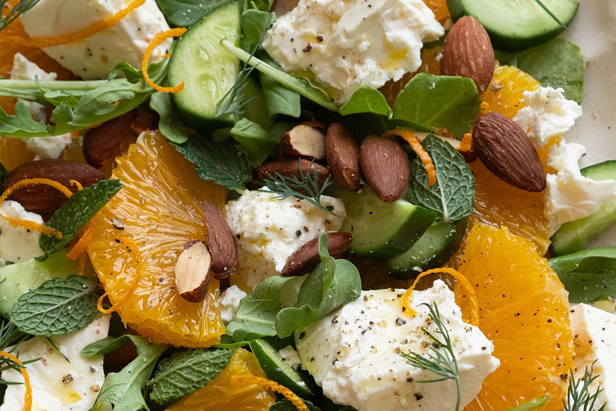 A plate of orange salad with feta, cucumber and herbs