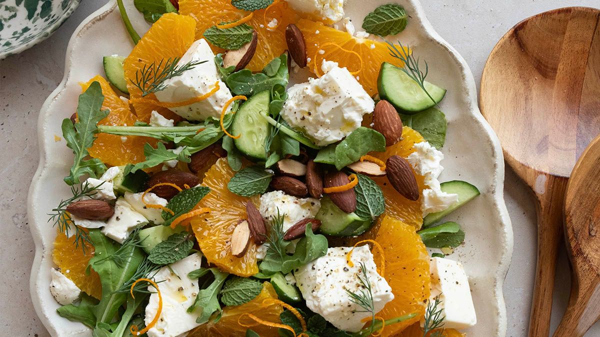 A plate of orange salad with feta, cucumber and herbs