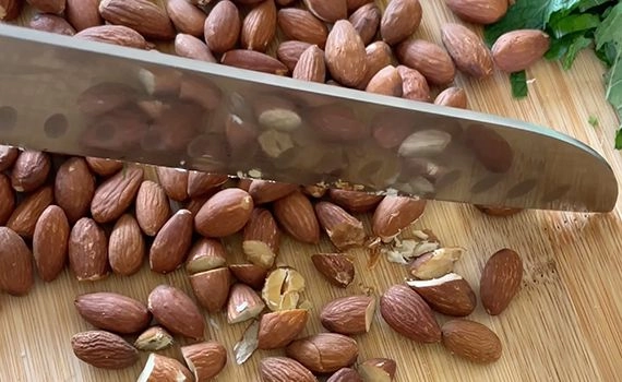 Chopping almonds on a board with some chopped mint of to the top right corner
