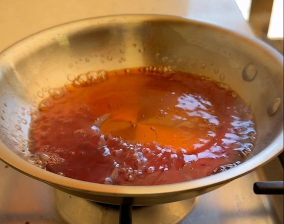 Simmering the agrodolce sauce in a pan.