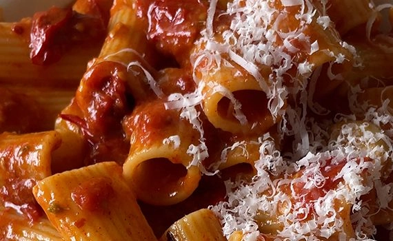 A close up of the roasted tomato rigatoni arrabbiata, garnished with grated parmesan cheese